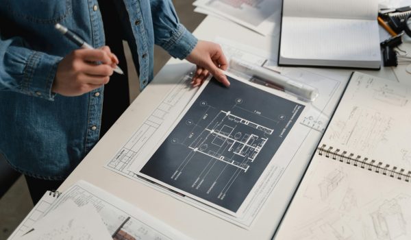 pexels-photo-6615234-6615234 Engineer reviewing architectural blueprints on a desk with technical drawings.